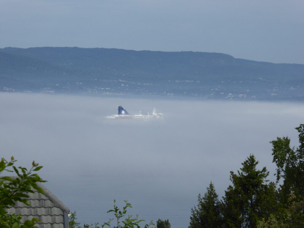 View of the Oslofjord. Boat barely visible in dense fog